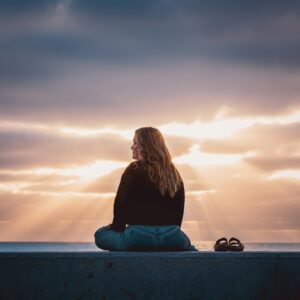 Photo by Joel Danielson A woman sitting on a wall looking at the sky